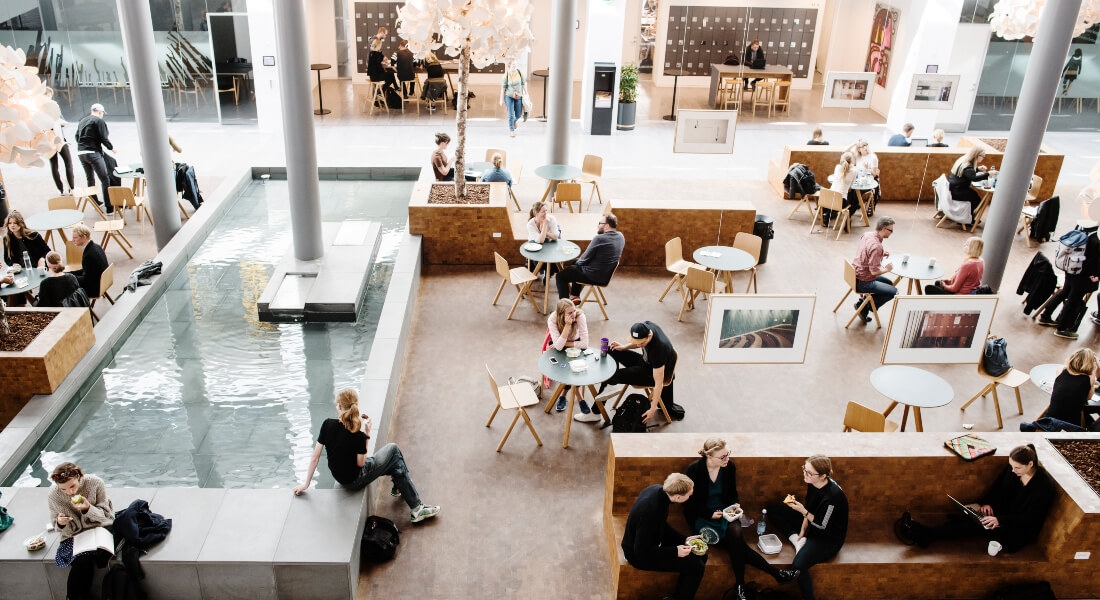 Overbliksbillede af et fællesareal på Søndre Campus med borde, stole og et bassin.